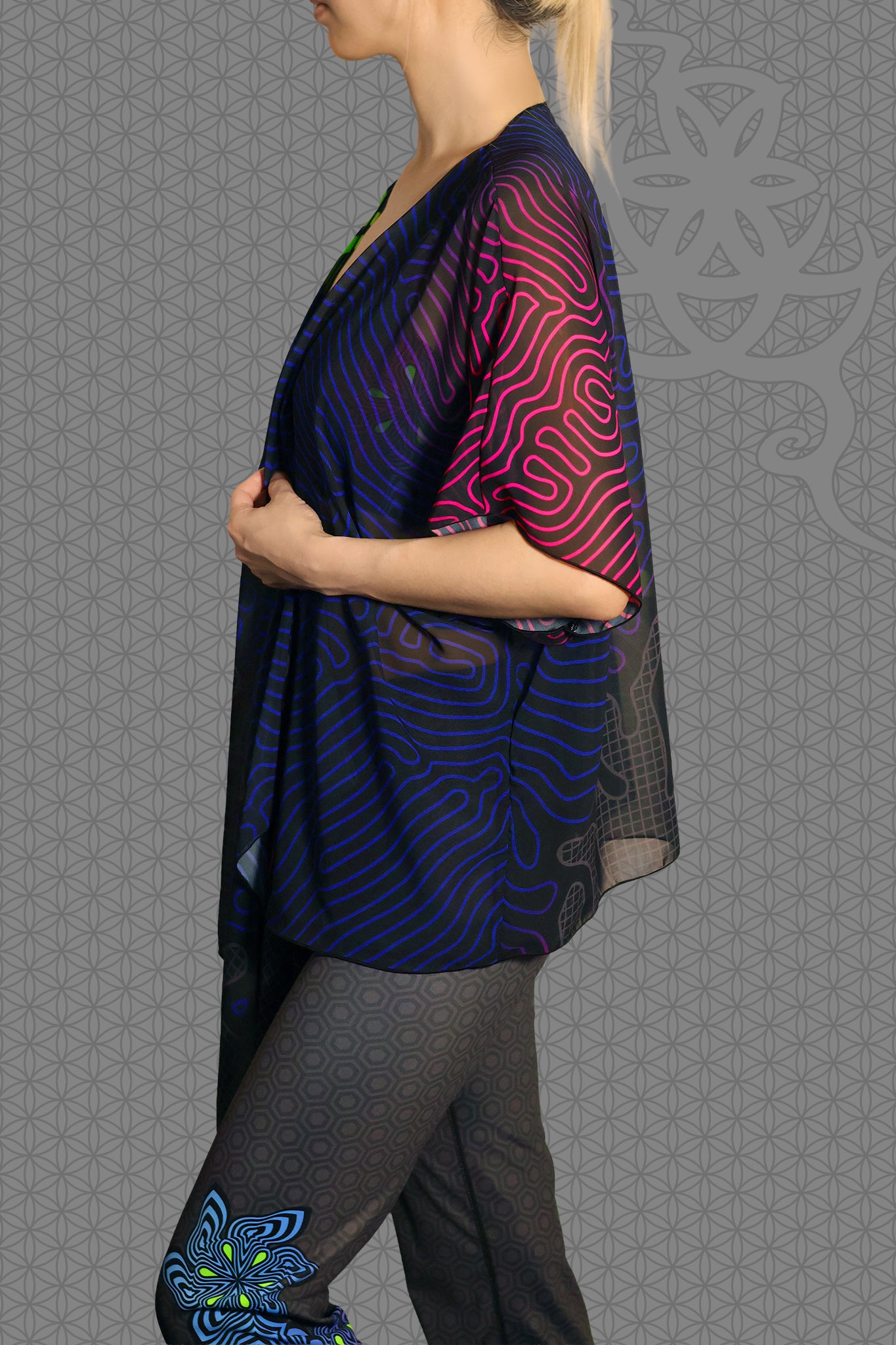 left view sheer chiffon psychedelic rave kimono with neon green, blue, and pink contour patterns on black worn over festival outfit