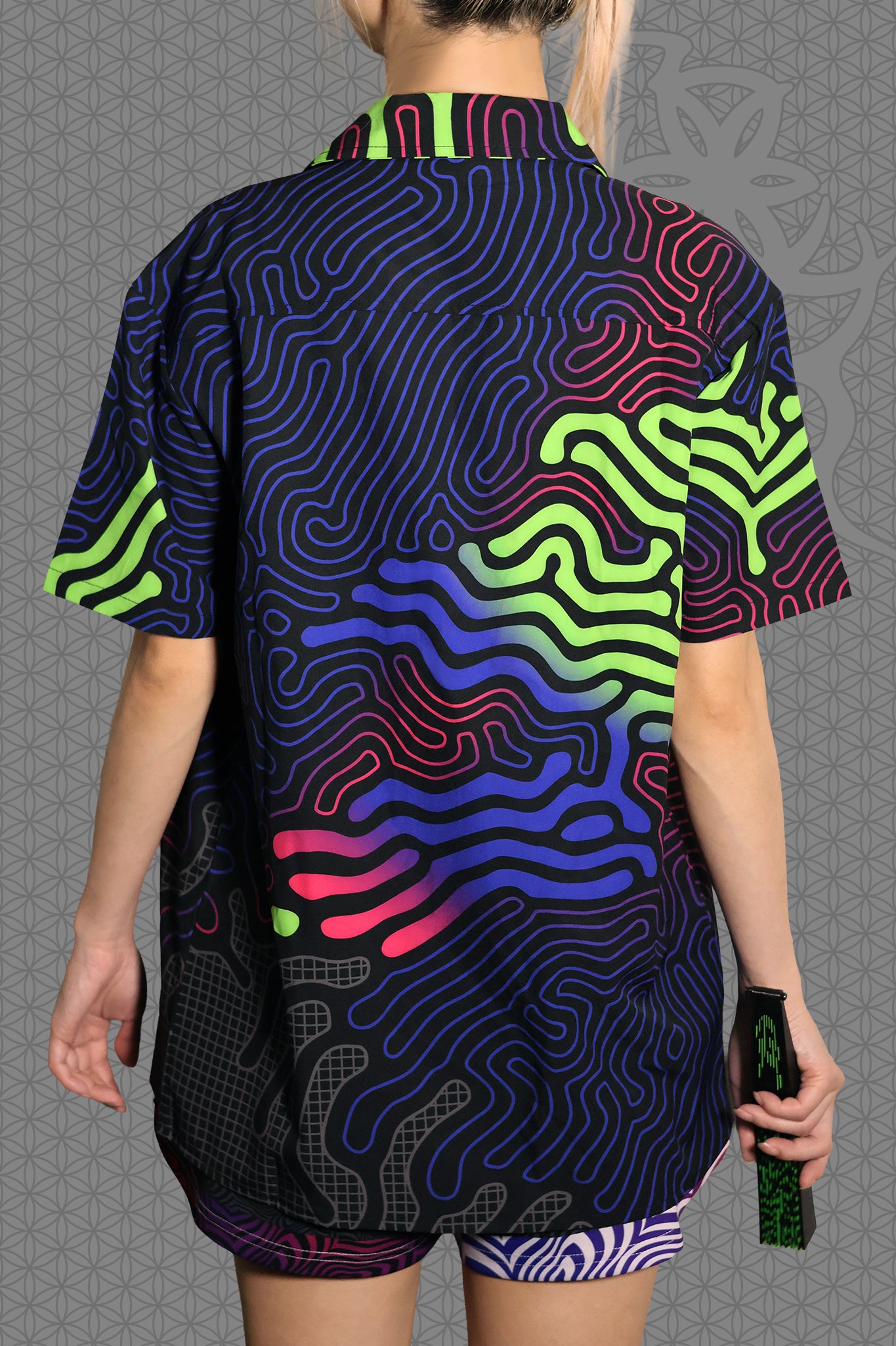 back view psychedelic short sleeve camp shirt with black base and flowing neon reaction diffusion patterns in green, pink, blue, and purple, featuring button front and spread collar