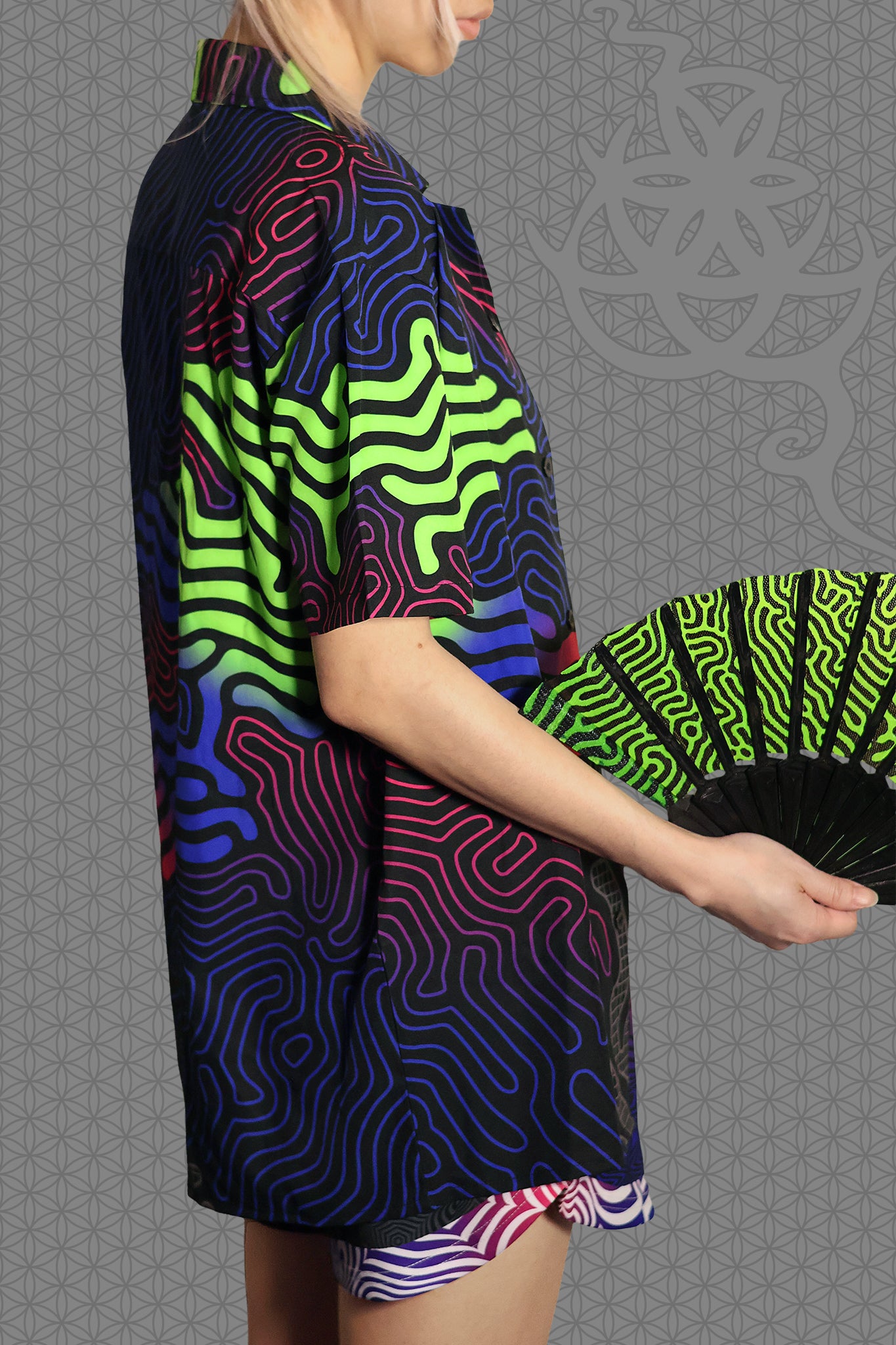 right view psychedelic short sleeve camp shirt with black base and flowing neon reaction diffusion patterns in green, pink, blue, and purple, featuring button front and spread collar