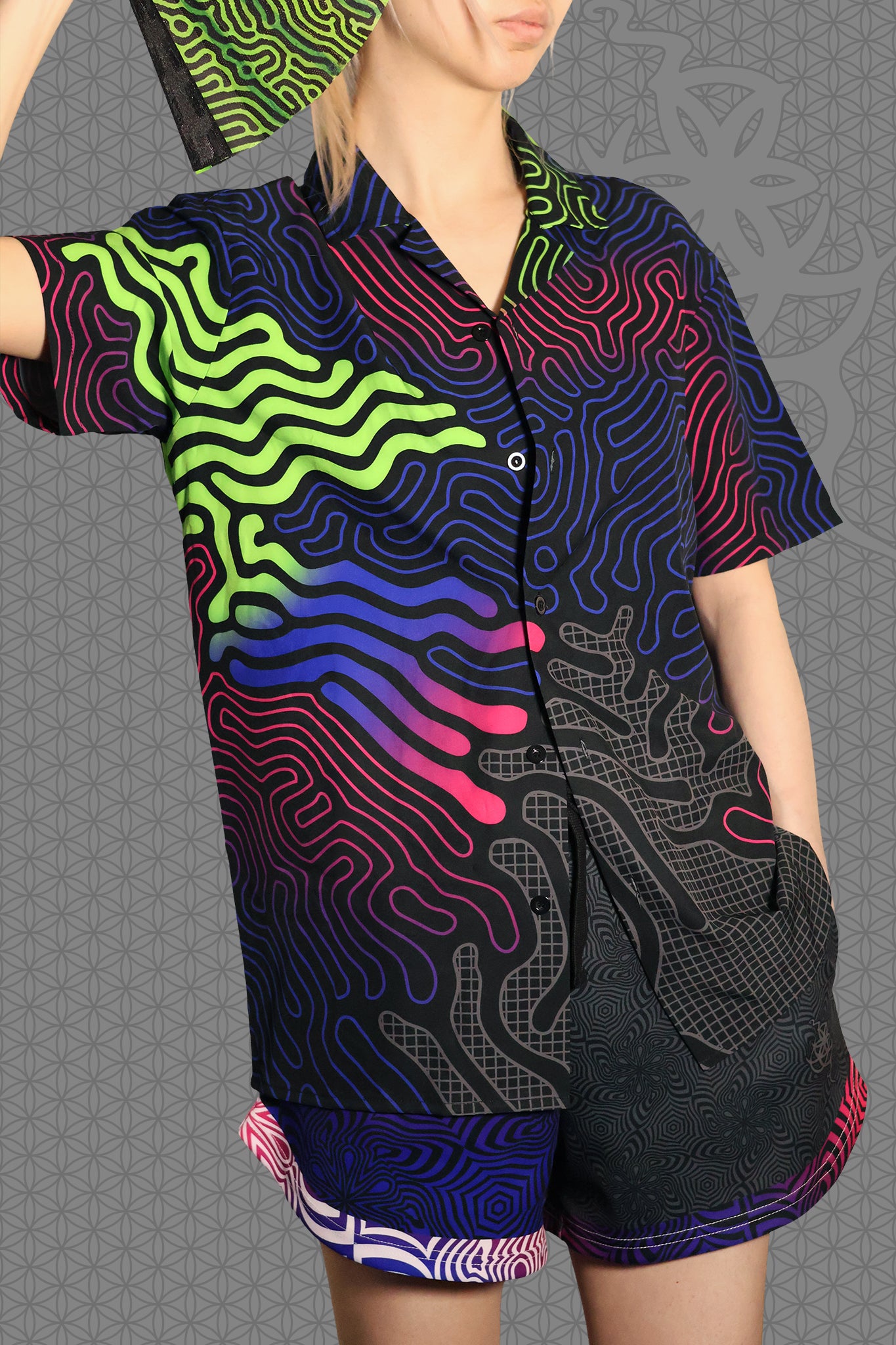 model view psychedelic short sleeve camp shirt with black base and flowing neon reaction diffusion patterns in green, pink, blue, and purple, featuring button front and spread collar