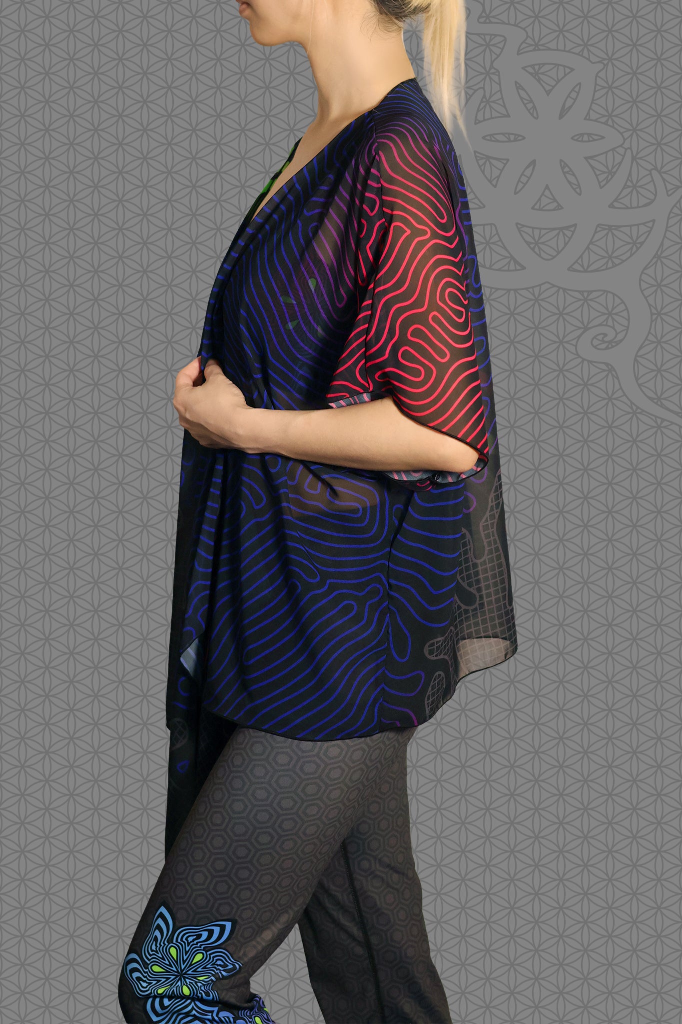 left view sheer chiffon psychedelic rave kimono with neon green, blue, and pink contour patterns on black worn over festival outfit