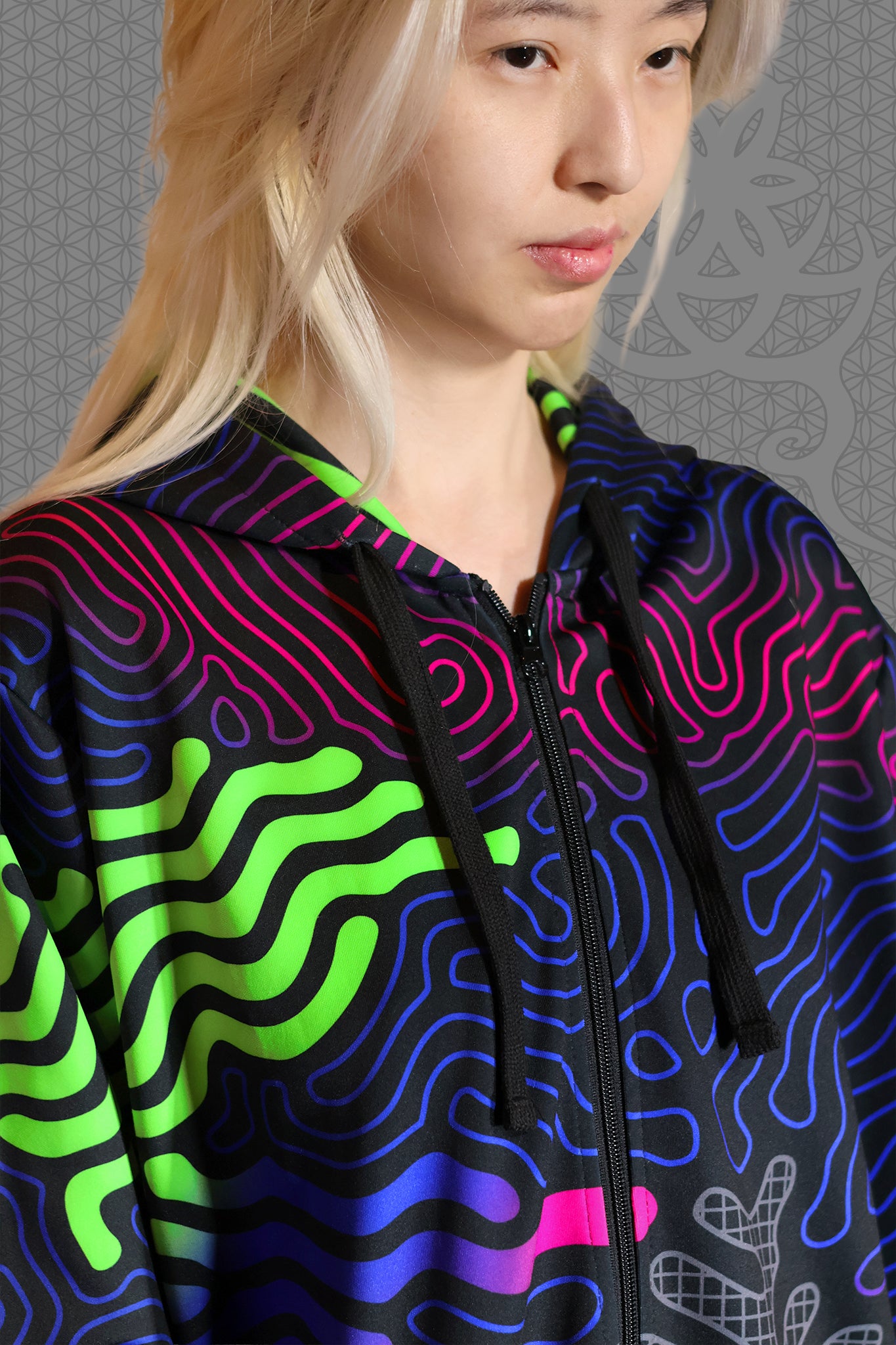 close-up view psychedelic rave zip hoodie with neon green, blue, and pink contour patterns on black with black fleece interior lining
