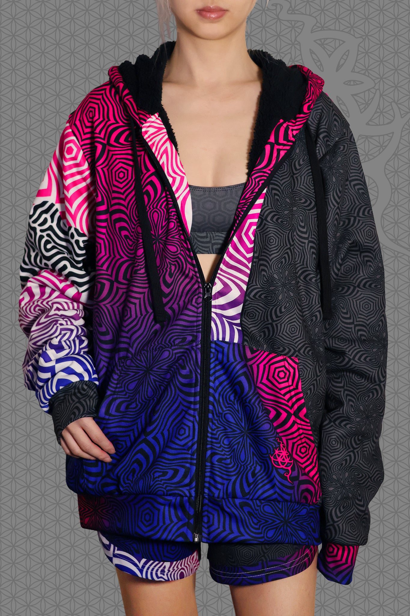 front view psychedelic rave zip hoodie with neon pink, purple, and blue geometric optical patterns and black panel design with black fleece interior lining