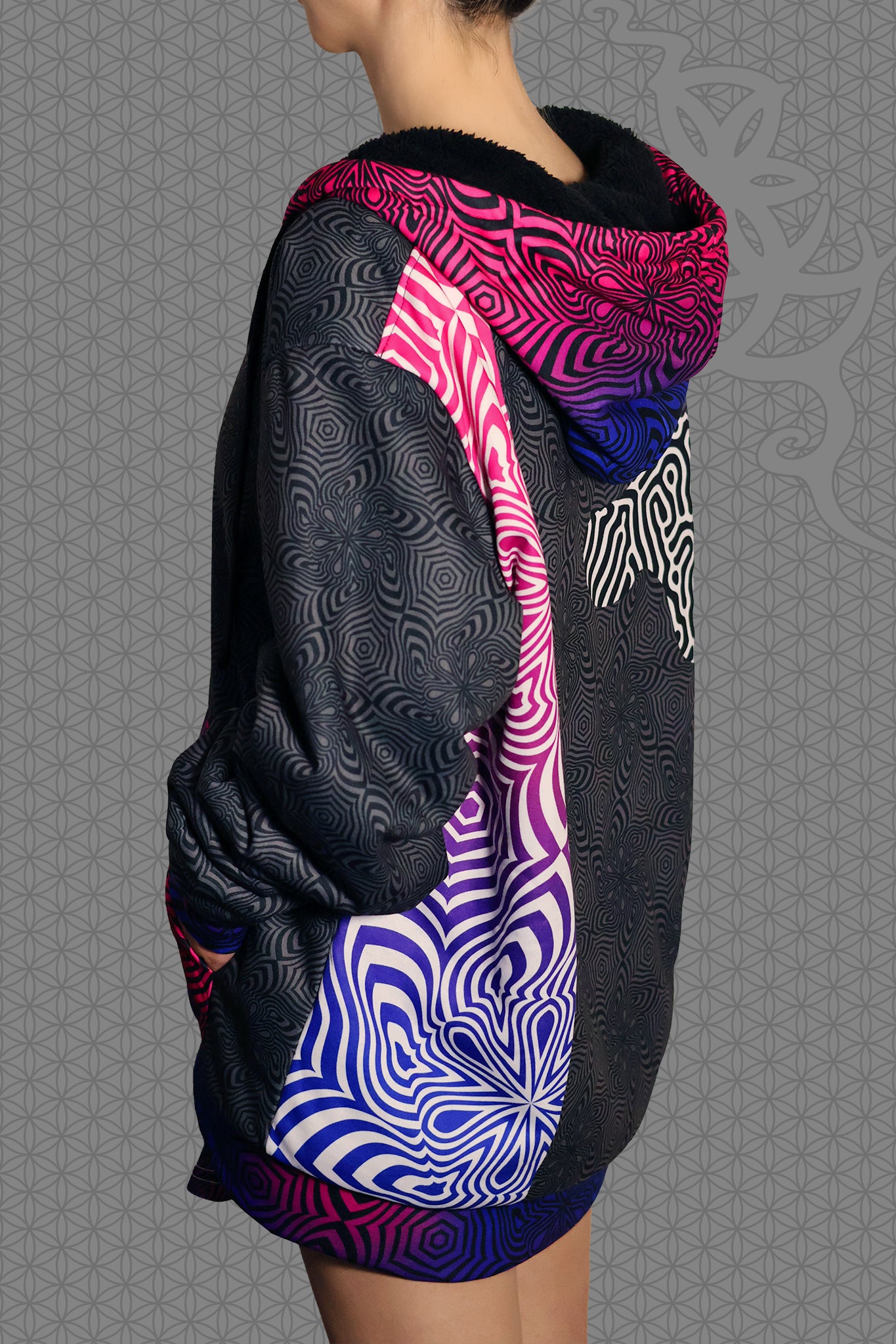left view psychedelic rave zip hoodie with neon pink, purple, and blue geometric optical patterns and black panel design with black fleece interior lining