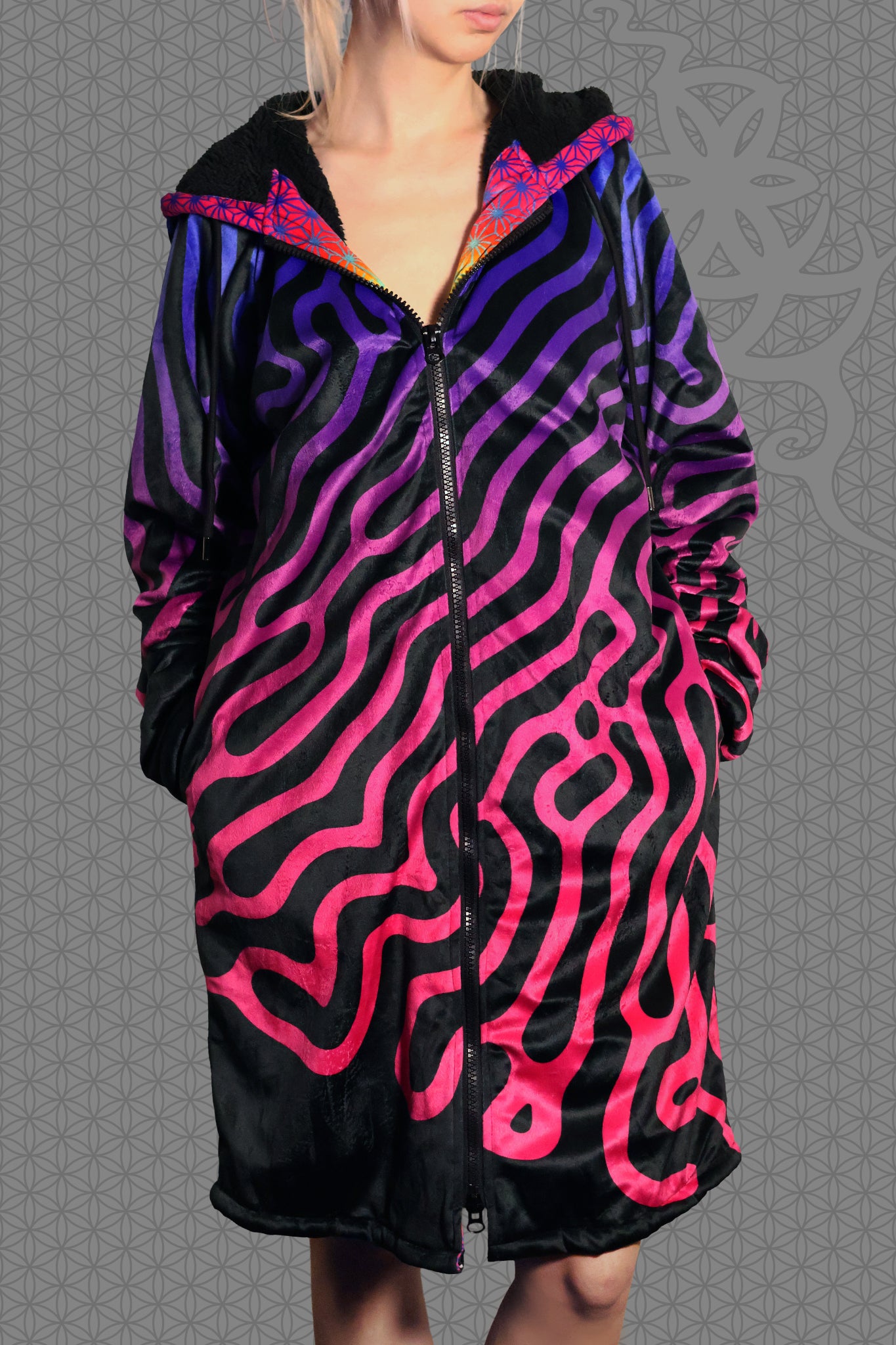 front view psychedelic hooded zip jacket with magenta-to-purple Turing pattern and reaction diffusion on black, contrasting rainbow geometric trim along the zipper and hood, and soft black fleece lining