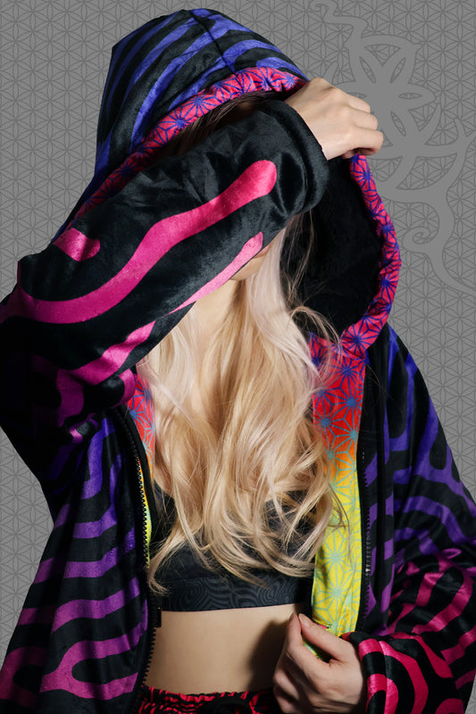 close-up view psychedelic hooded zip jacket with magenta-to-purple Turing pattern and reaction diffusion on black, contrasting rainbow geometric trim along the zipper and hood, and soft black fleece lining