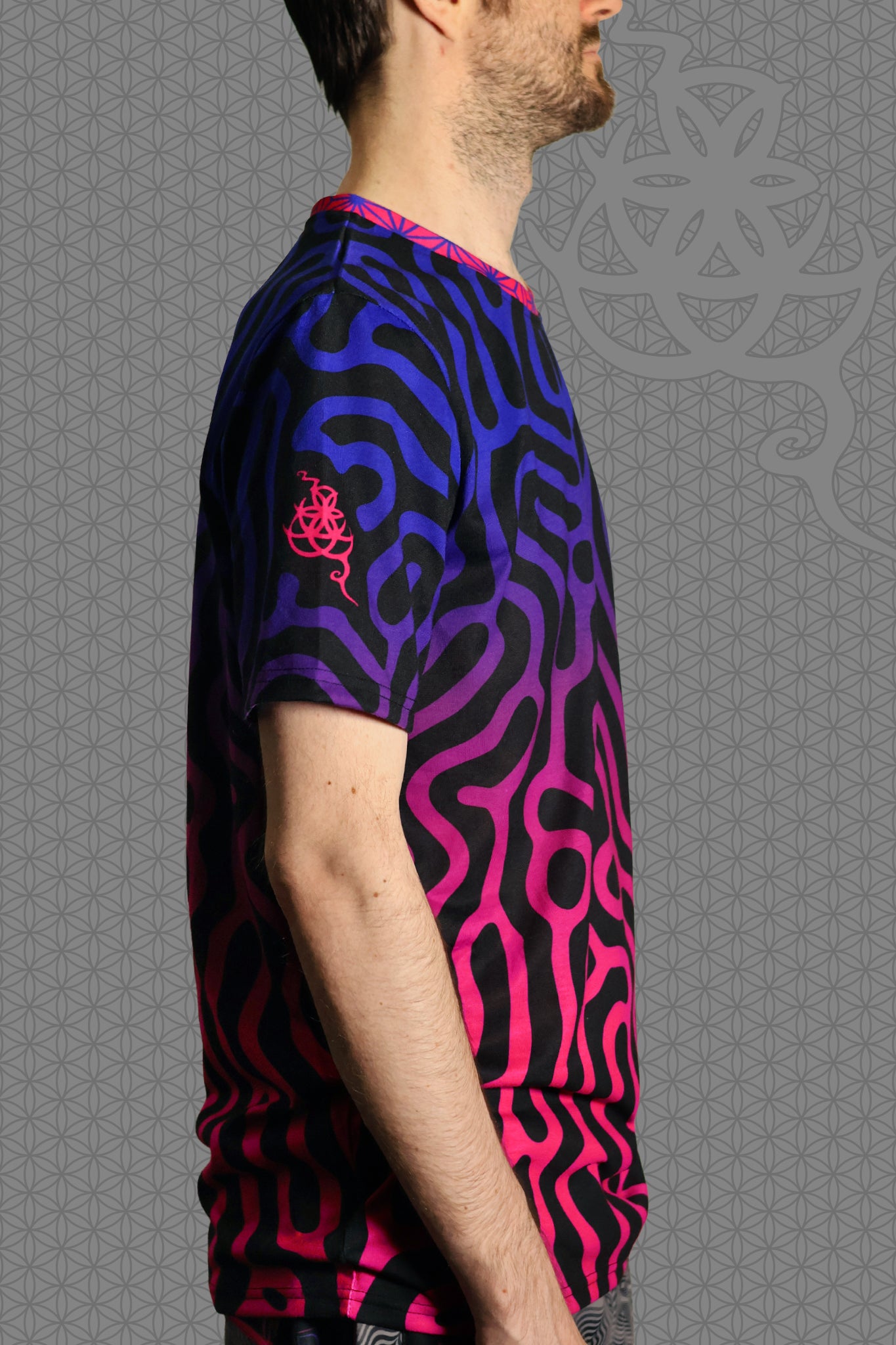 right view psychedelic short sleeve t-shirt with black base and flowing pink-to-purple gradient pattern, featuring contrasting rainbow geometric trim on the sleeve and collar