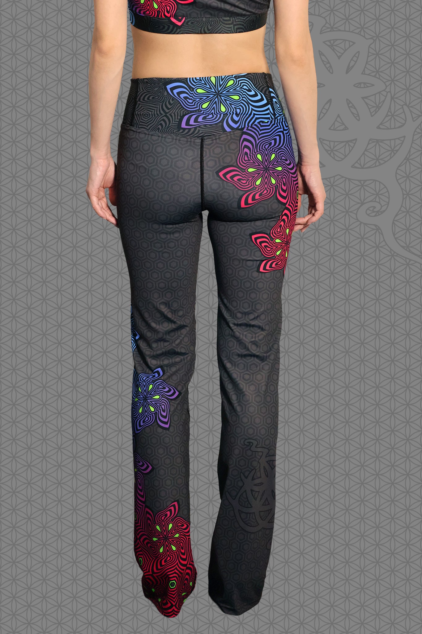 back view psychedelic rave flare leggings with neon pink, purple, blue, and green flower patterns on black